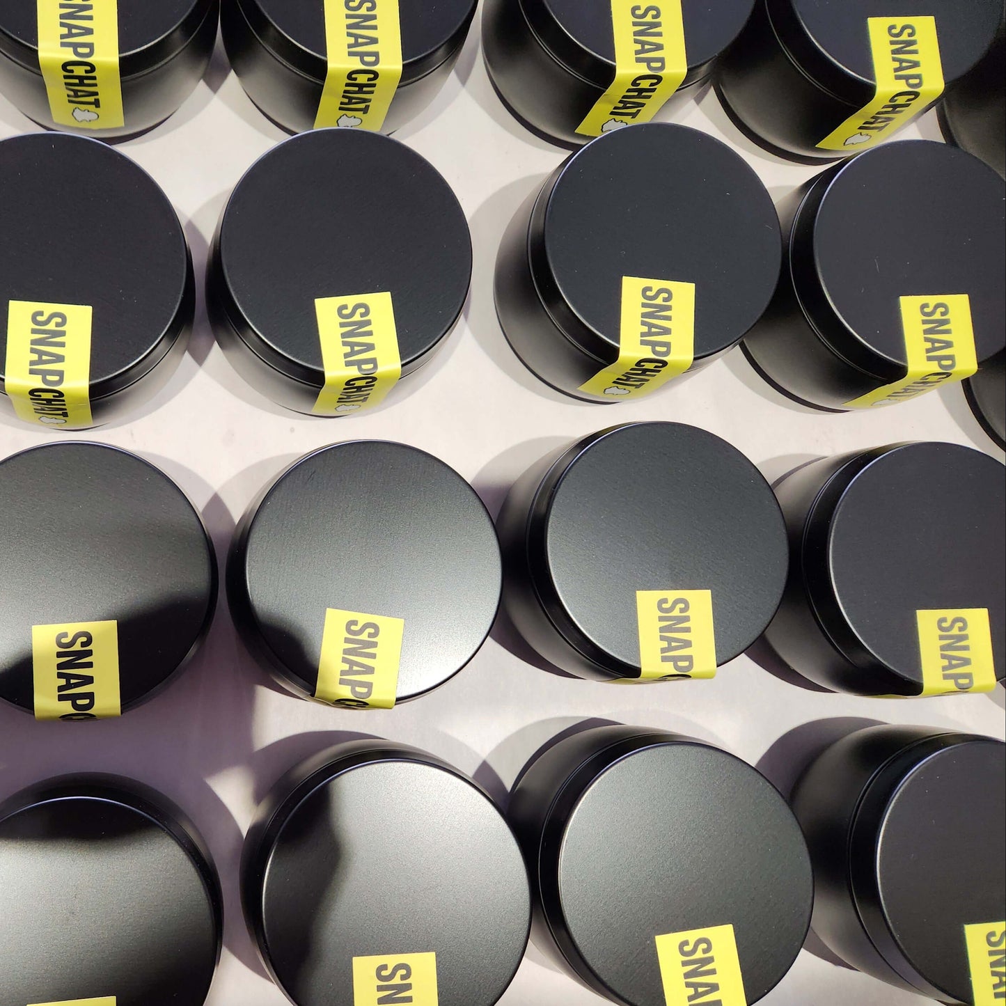 Fully branded 8oz black tin candles in production with yellow custom labels