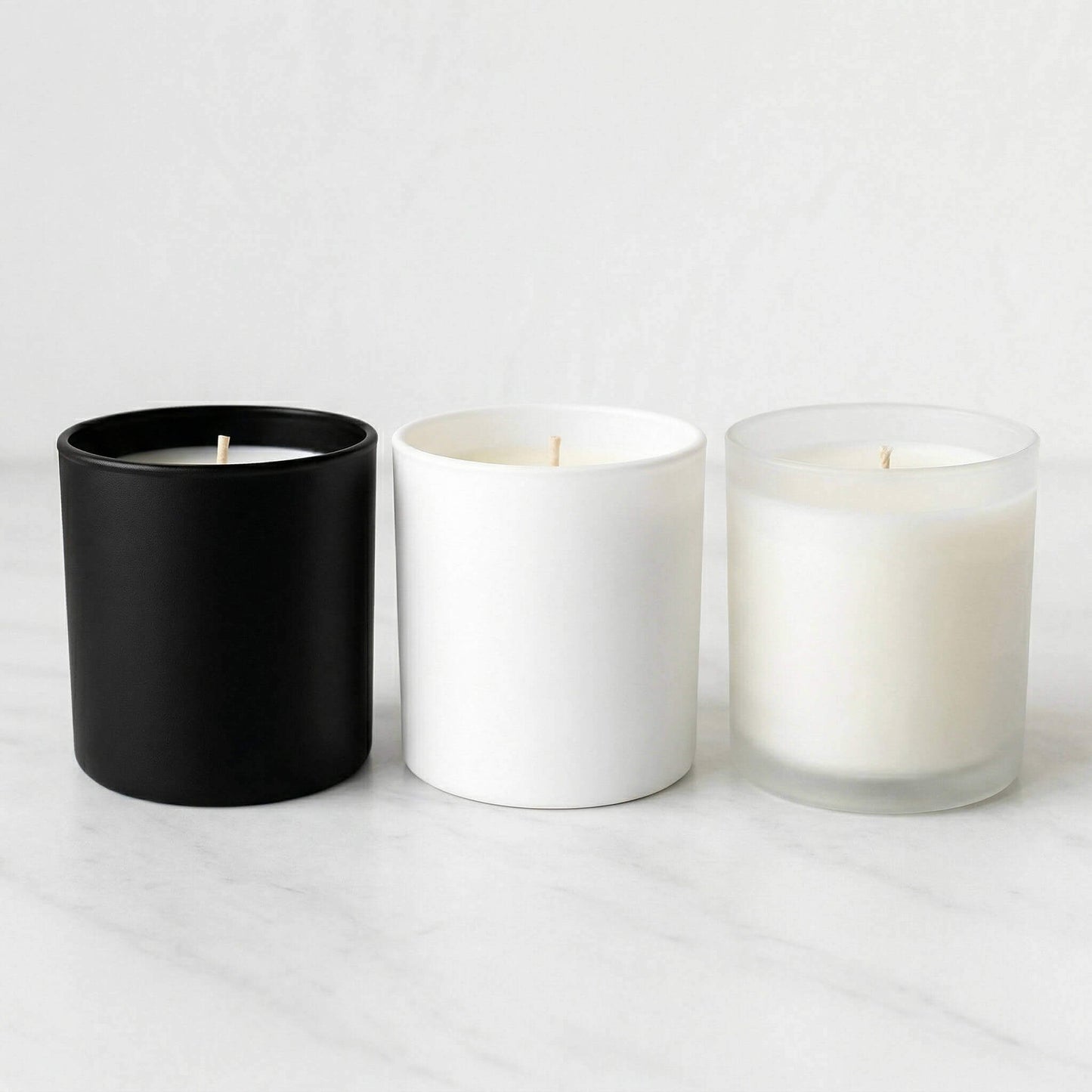 Three unbranded candles in black, white, and clear containers on a light gray background